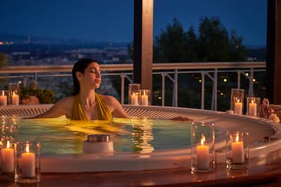 Frau, die sich im Außenpool bei Kerzenschein entspannt