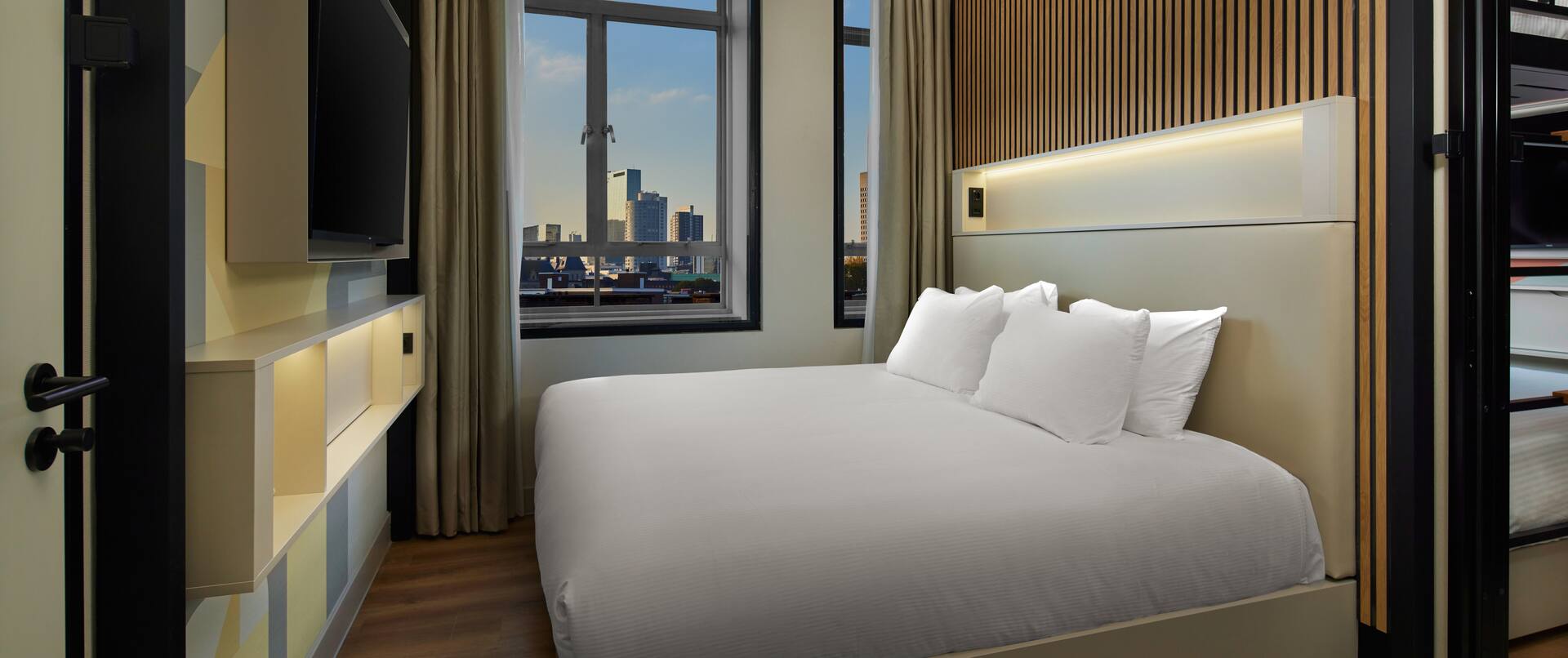 a large bed in a room with HDTV and city view