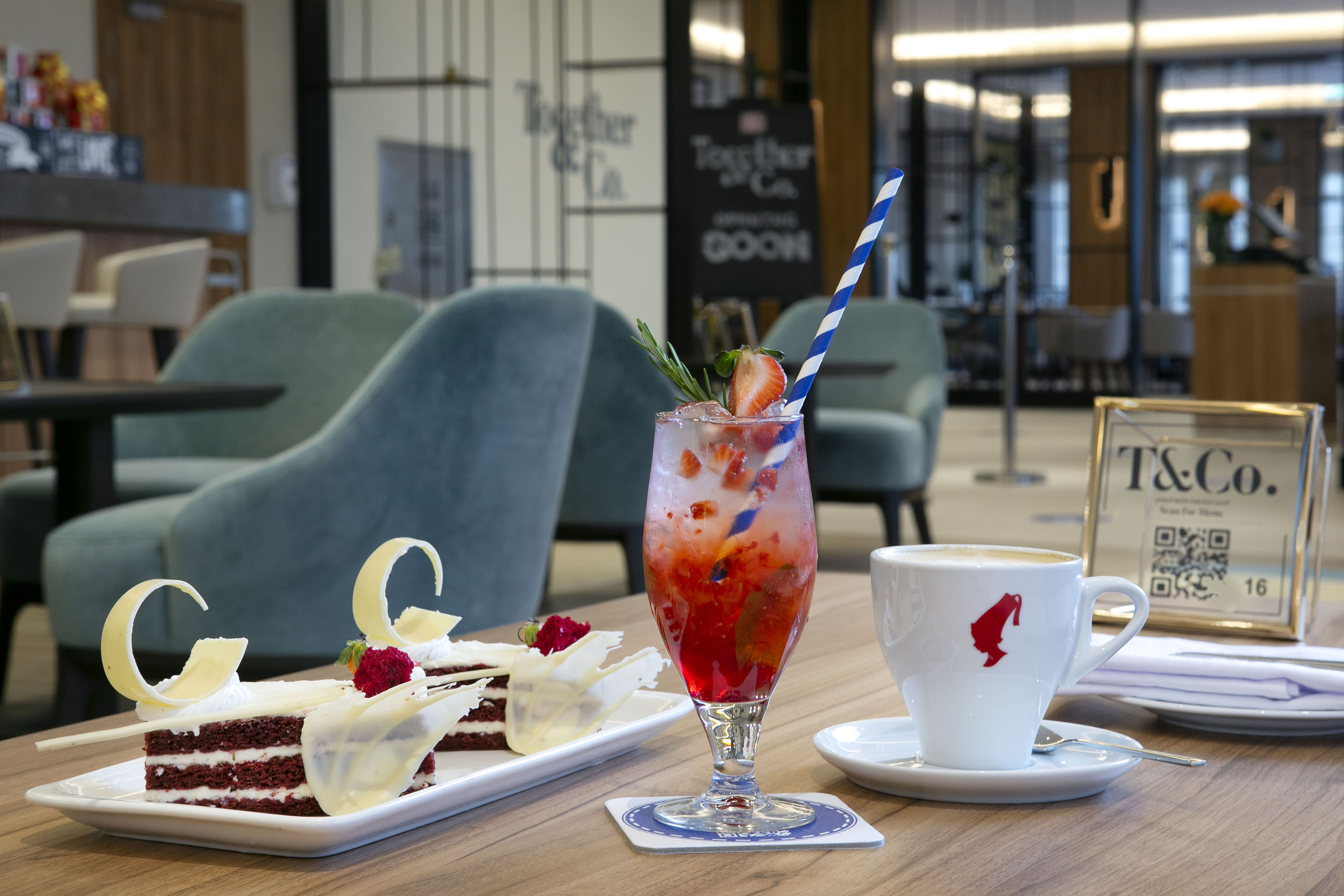 Close-up of table in lounge with cakes, coffee and fruit drink