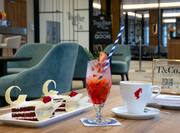 Close-up of table in lounge with cakes, coffee and fruit drink