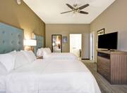CEiling Fan Above Two Queen Beds, Full Length Mirror, Open Door to Bathroom, and TV in Executive Suite