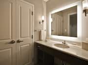 Closet With Double Doors, Brightly Lit Vanity Mirror, Sink With Fresh Towels, Toiletries, and Amenities in Suite Bathroom