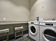 Folding Table, Two Stools, and Coin Operated Washing and Drying Machines in Laundry Facility 