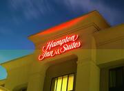 A Hotel Exterior with a Light Up Neon Hampton Inn & Suites Sign