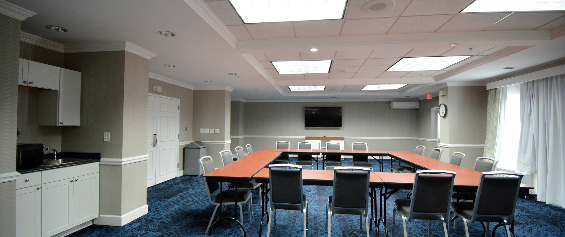 Conference Center in a Square Seating Set Up with a Wet Bar including a Microwave and Large Screen