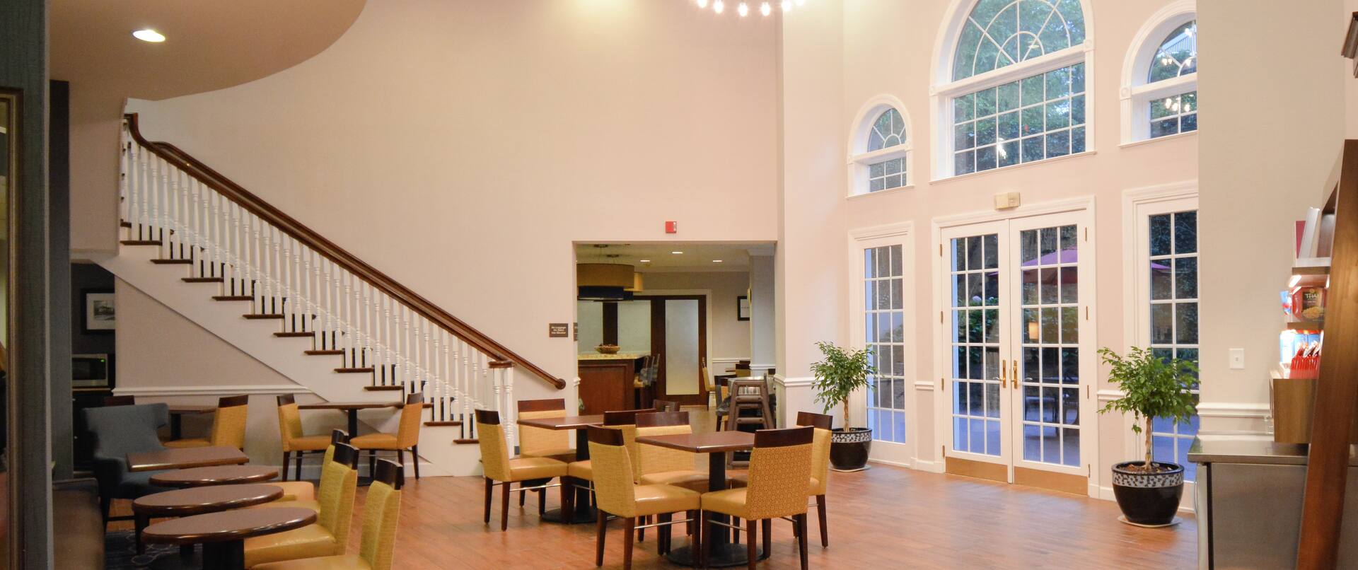Breakfast Area in Lobby with Glass Doors to Patio and Large Staircase in Background