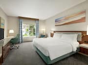 Spacious private bedroom in suite featuring comfortable king bed, work desk, and outside view.