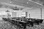 Spacious on-site ballroom featuring ample classroom style seating, large window, and projector screen at front of room.