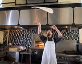 Chef throwing pizza dough at NY West
