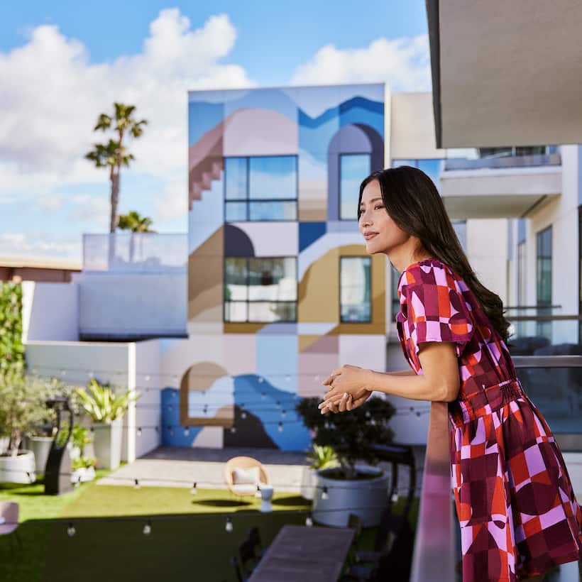 Women leaning on balcony railing and smiling as she looks out over hotel grounds