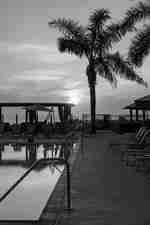 Изглед към басейна при залез слънце, с дървета и места за сядане