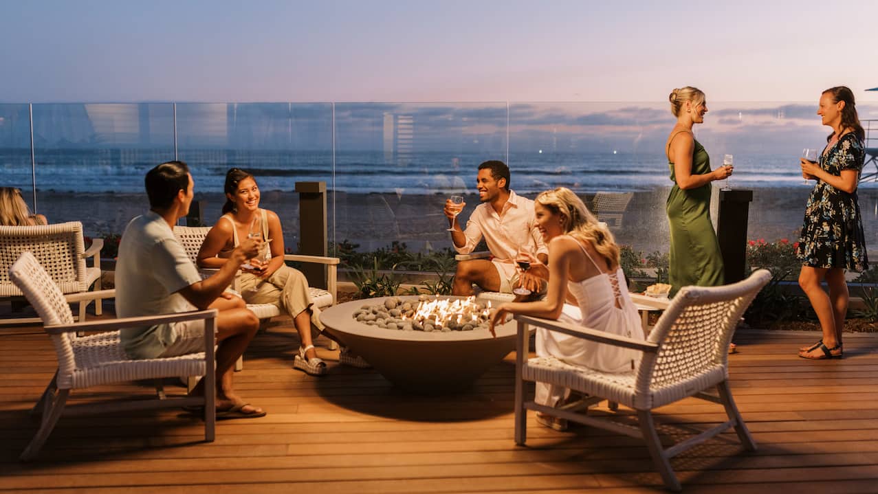 group of people having drinks by outdoor fire pit