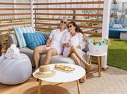 couple sitting in cabana with drinks and food