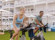 man and woman outdoors using stationary bikes