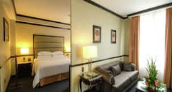 Junior Suite with View of Bed and Living Area with Sofa, Coffee Table, Table Lamp, and Outside View