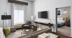 Suite living room with wall mounted TV and door to bedroom