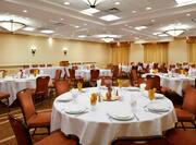 Chairs, Place Settings, Decorative Centerpieces, and White Linens on Round Tables in Ballroom Set Up for Banquet