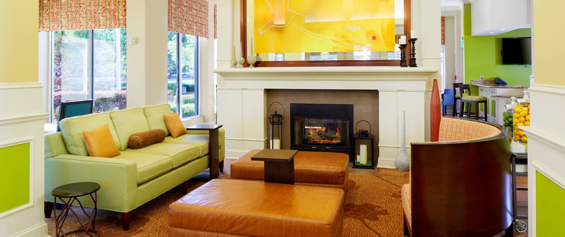 Wall Art and Soft Seating Around Fireplace in Lobby With Large Windows