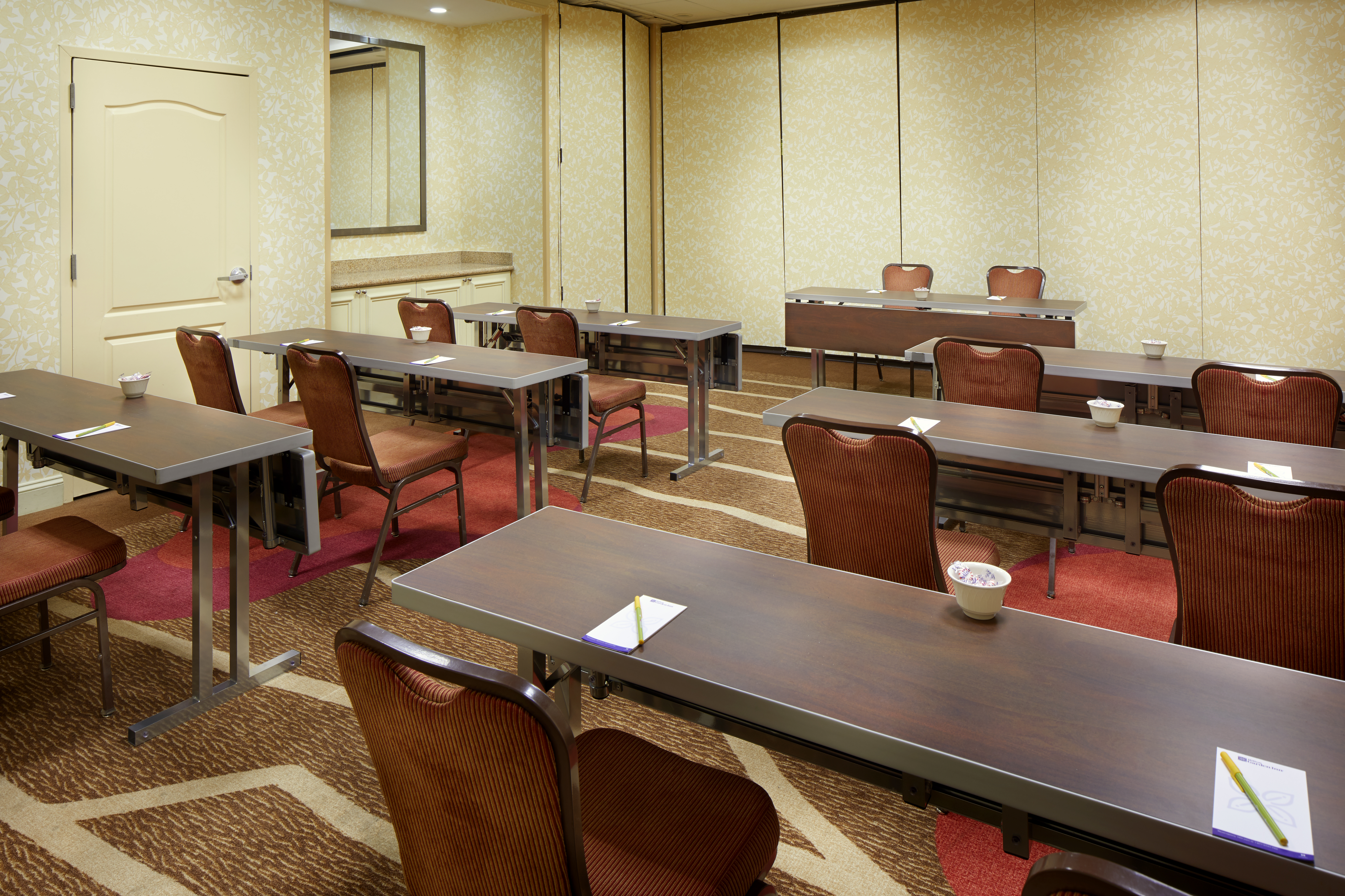 Classroom Setup in Meeting Room With Tables and Chairs Facing Speaker's Table and Two Chairs