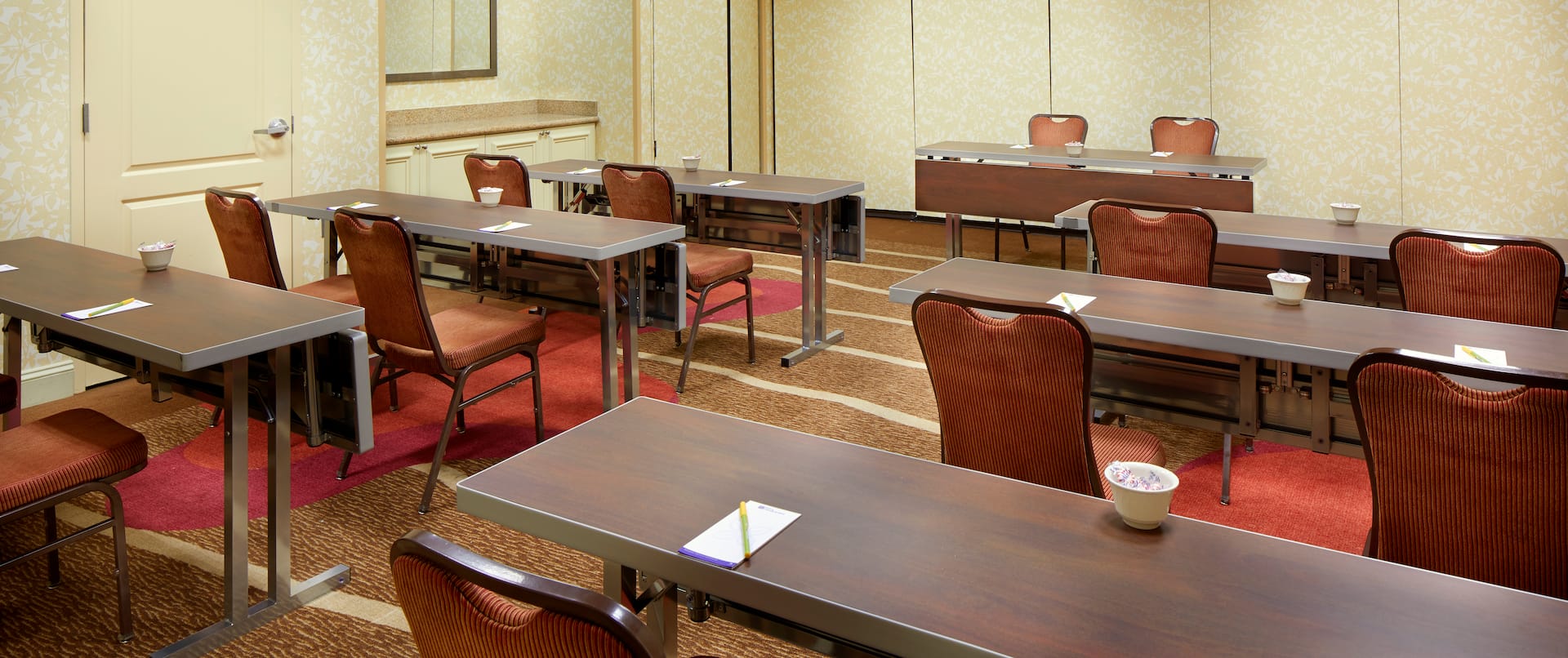 Classroom Setup in Meeting Room With Tables and Chairs Facing Speaker's Table and Two Chairs