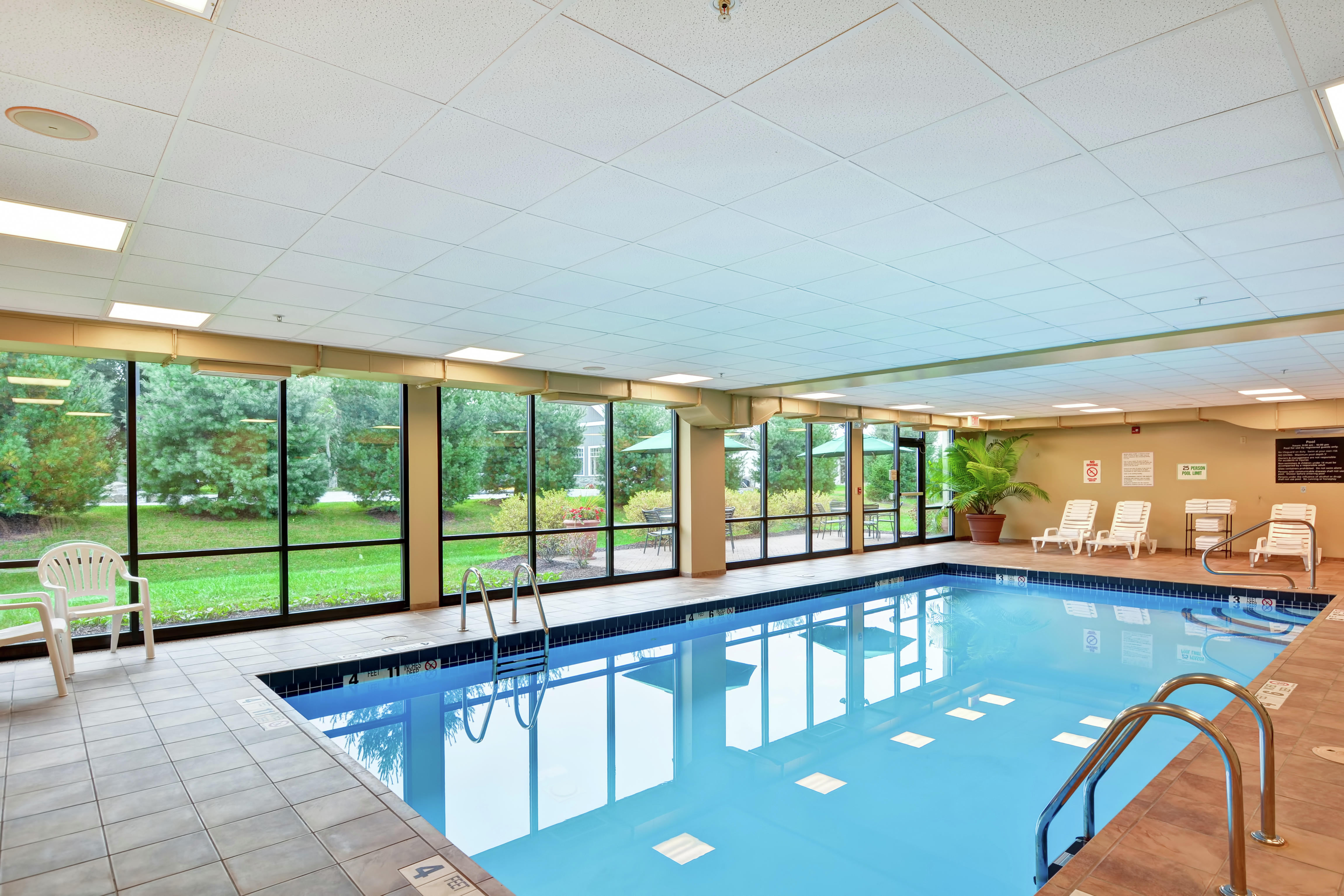 Indoor Swimming Pool Area with Large Windows and Lounge Chairs