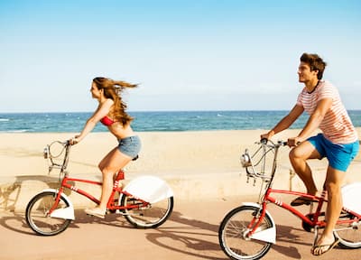 Man and Woman Riding Bikes Along Beach