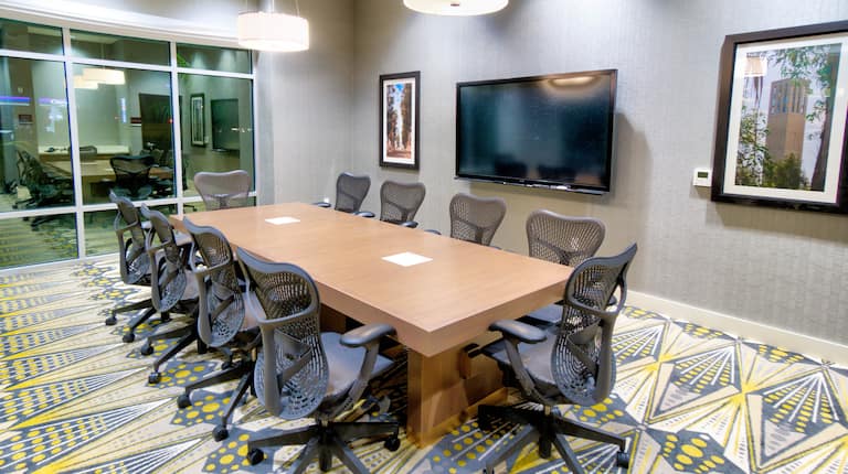 View of Meeting Room Space with Office Chairs, Table and Wall Mounted HDTV