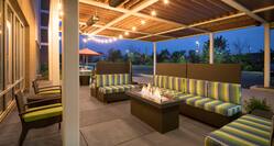 Outdoor patio area lit up with sofas and lounge chairs surrounding fire pit