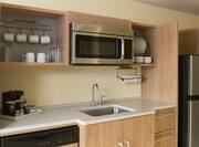 Guest room kitchen with sink, dish washer, microwave, fridge, coffee maker, and dining amenities