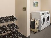Laundry facility with partial view of free weights in fitness center