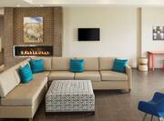 Lobby seating area with L-shaped sofa, ottoman, TV, and fireplace