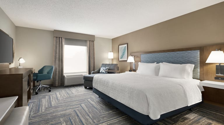 Spacious guestroom featuring comfortable king bed, TV, and work desk.