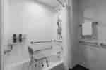 Amplia bañera accesible para personas con discapacidades con asiento y barras de apoyo para facilitar el acceso a los huéspedes