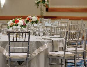 Wedding Reception Setup With Floral Centerpieces and Place Settings on Round Banquet Tables