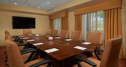 Conference Room Boardroom Set Up with Office Chairs, Large Table, Notepads and Wall Mounted HDTV