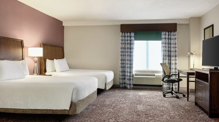 Spacious  suite featuring two comfortable queen beds, work desk, and TV.