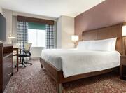 Spacious guestroom suite featuring comfortable king bed, TV, and work desk.