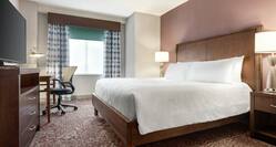 Spacious guestroom suite featuring comfortable king bed, TV, and work desk.