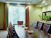 Wall Art, Window With Open Drapes, Wall Mirror Above Refreshment Station, and Boardroom Table With Flowers