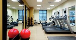 Fitness Center With Red Exercise Ball, Large Mirrors, Weight Balls, Free Weights, Weight Bench, Window, and Cardio Equipment
