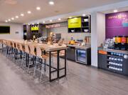 Breakfast serving and dining area with coffee, juice, cereals, oatmeal, fruits, and dining amenities