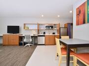 In-room kitchenette with dining table, chairs, TV, and work desk