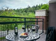 Fruit Tray, Wine Bottle, and Two Glasses of Wine on Table and Two Chairs on Suite Patio 