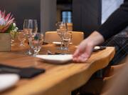 DoubleTree Restaurant - A detail shot of a rustic dinner table with place settings. A hand is arranging a plate.