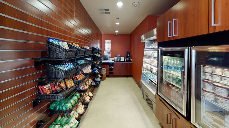 Área de compras con exhibiciones de refrigerios y estantes