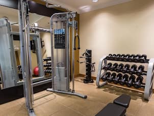 Fitness Center With Large Mirror, Weight Machine, Free Weights, and Bench