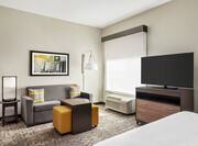 Bright studio suite featuring sofa, TV, and comfortable king bed.
