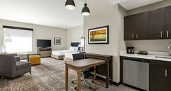 Spacious studio suite featuring fully equipped kitchen, work desk, lounge area, and two comfortable queen beds.