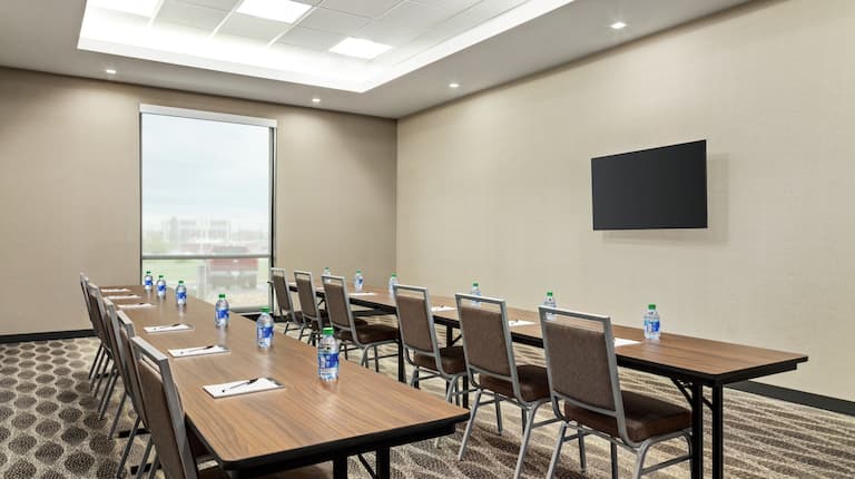 Spacious meeting room featuring classroom style seating, large window, and TV at front of room.