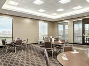 Spacious meeting space featuring round tables, ample seating, and large windows.